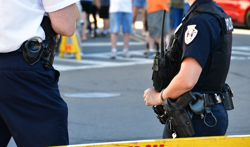 Police officer stands guard behind a barricade in a local community. Recent events show that police officers lack a connection to communities they serve.